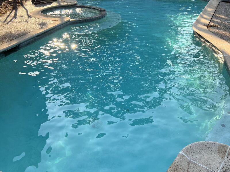 Pool with stone waterfall feature serviced by Retro Ink Pools in Cypress TX